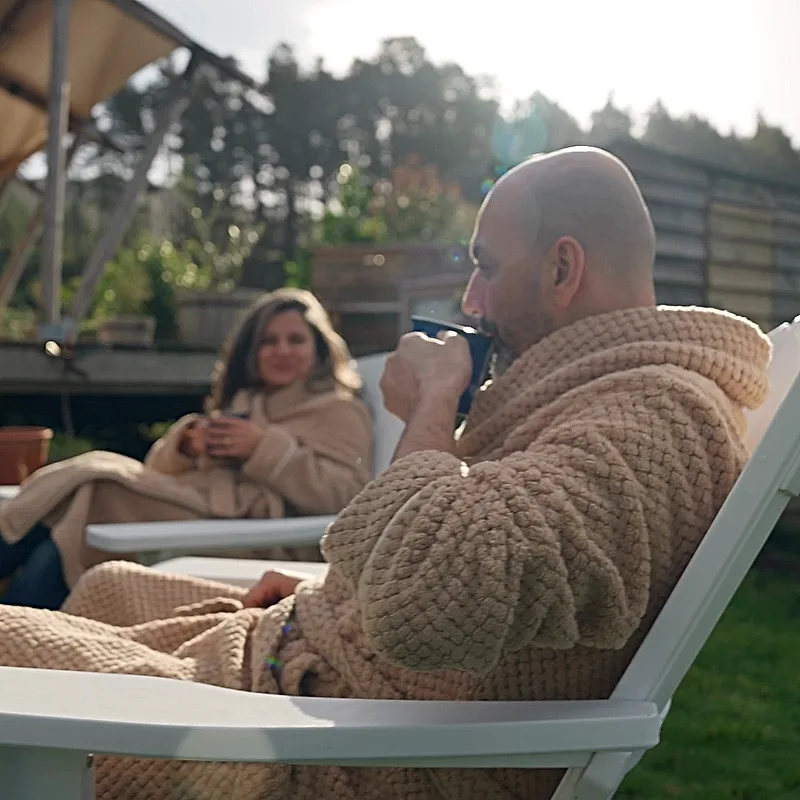Guests in dressing gowns sharing a slow morning coffee outside the safari tent