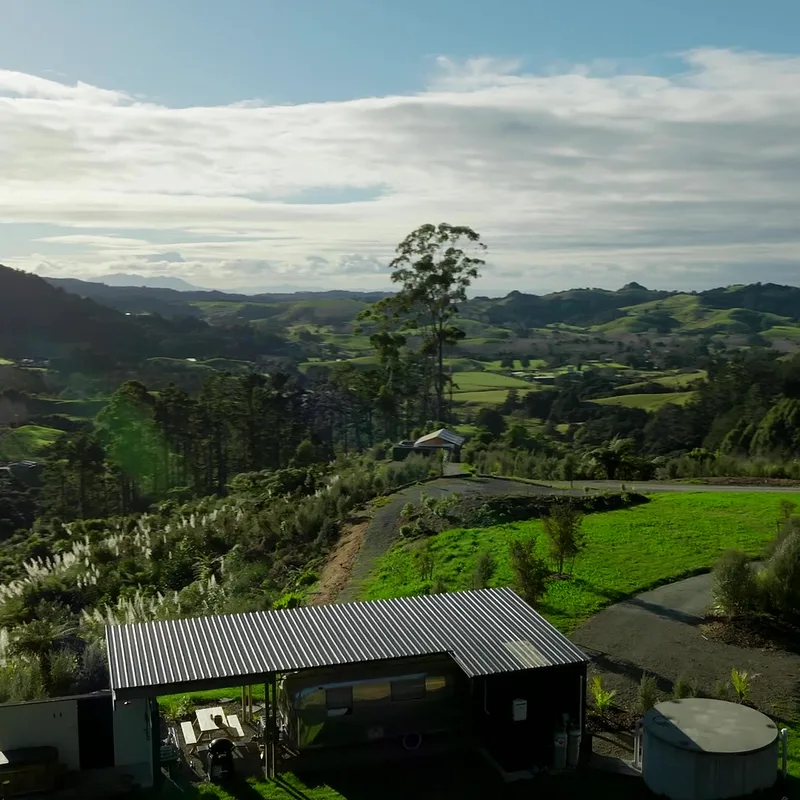 The Airstream under its canopy, looking out over the rolling Matakana valley