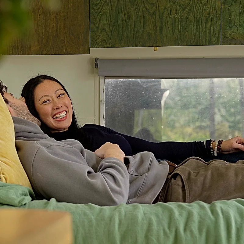 A couple laughing together on the bed inside the Airstream
