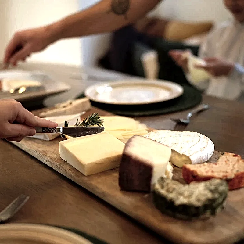 Hands reaching for a cheese board on the eco-lodge dining table